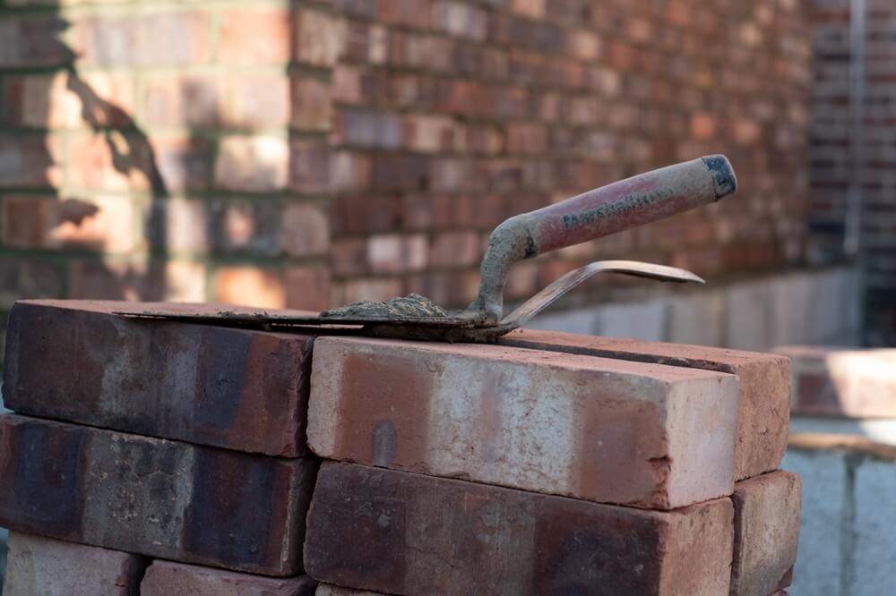 Bricklaying trowel resting on a stack of red bricks at a construction site