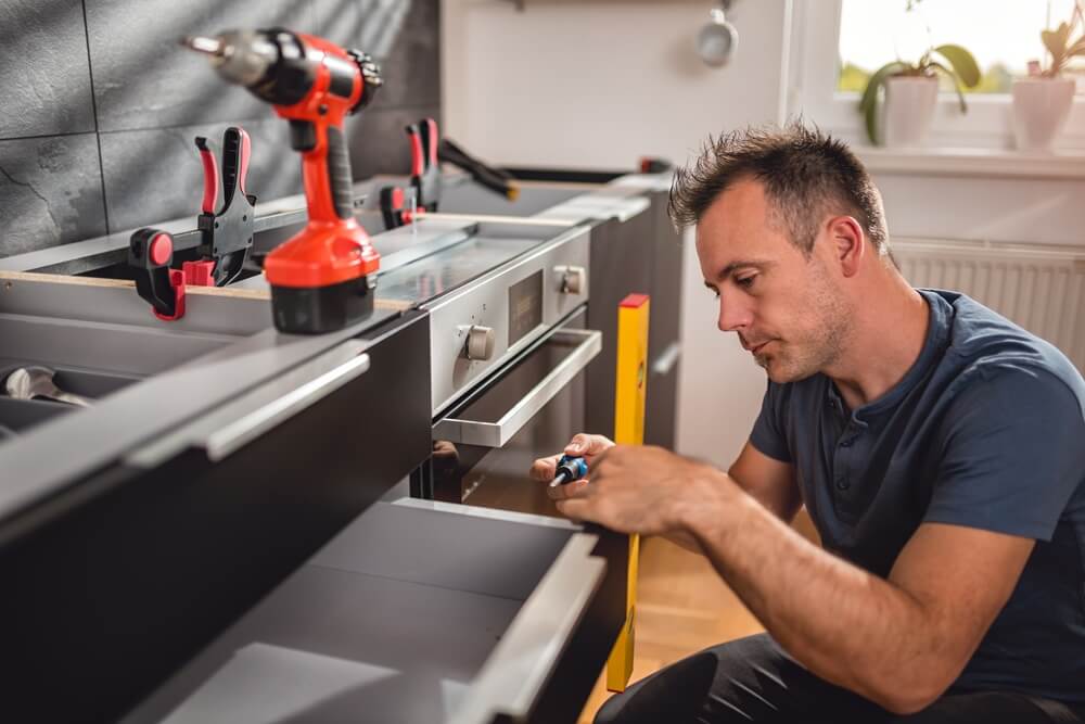 Kitchen installer fitting a drawer cabinet during a modern kitchen installation.