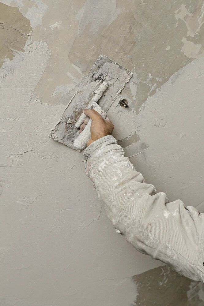 Plasterer’s hand applying plaster with a trowel to an interior wall — showcasing craftsmanship promoted through effective marketing.