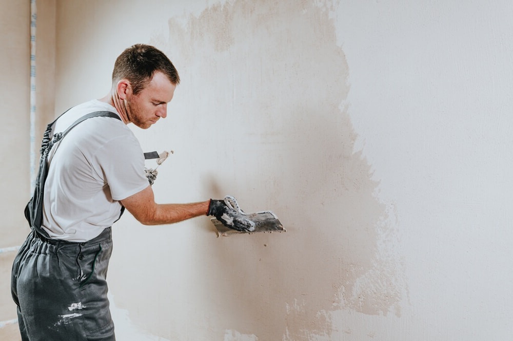 Plasterer smoothing an indoor wall with a float—representing skilled craftsmanship and the type of service TradePal promotes.