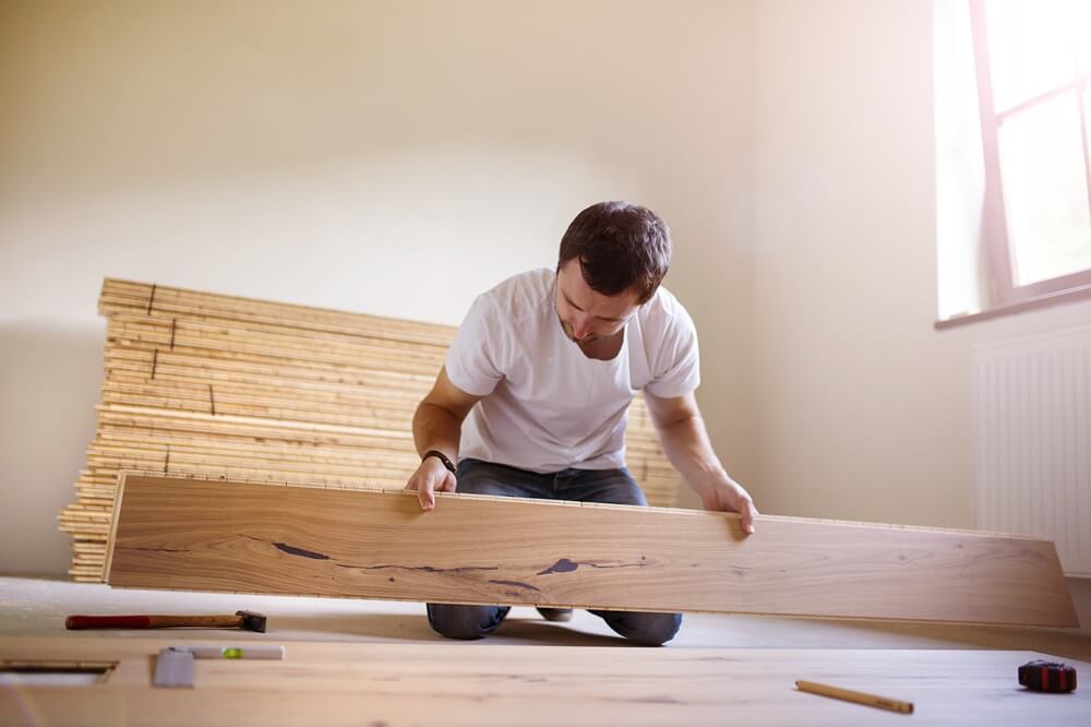 Flooring contractor fitting timber floorboards during a home flooring installation.