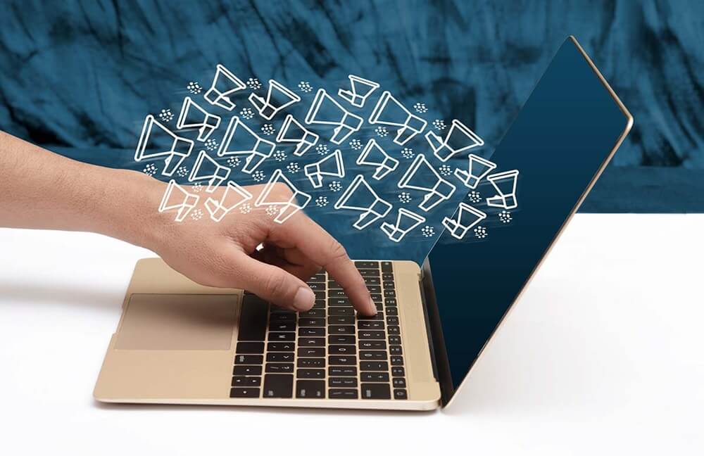 A hand typing on a laptop with illustrated email icons emerging from the screen, representing TradePal’s targeted email marketing campaigns for kitchen fitters to generate repeat business.